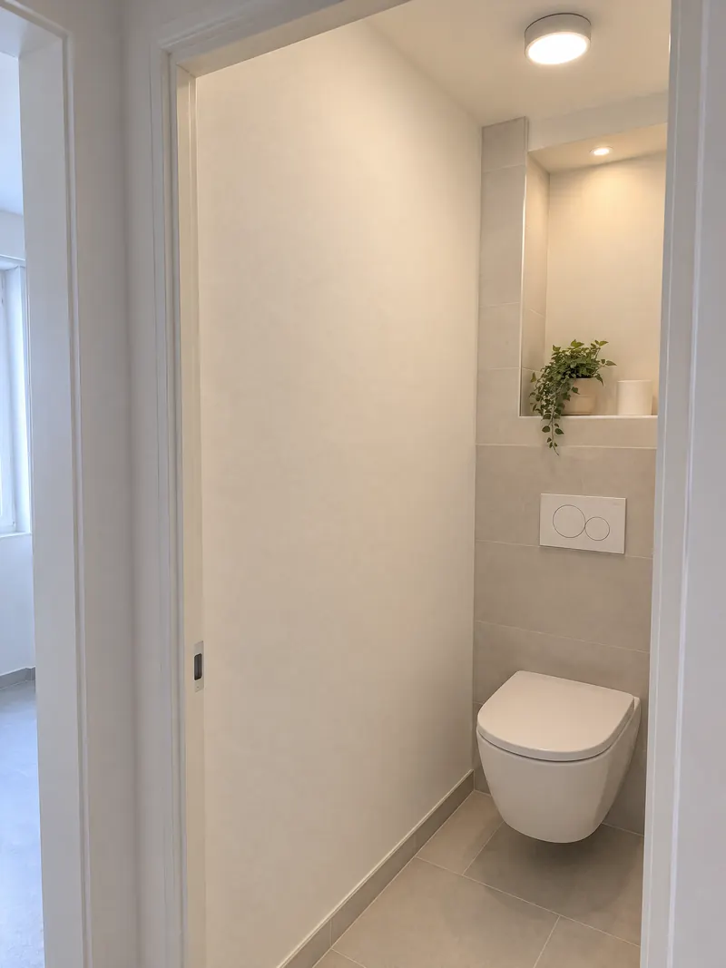 WC suspendu sur bâti-support habillé de carrelage gris clair, niche peinte au-dessus